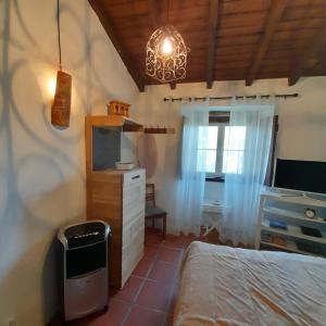 a bedroom with a bed and a tv and a window at Casa das Amoras in Santo António das Areias