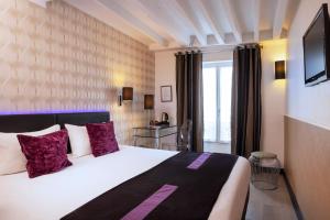 Pokój hotelowy z dużym łóżkiem z fioletowymi poduszkami w obiekcie ATN Hôtel w Paryżu