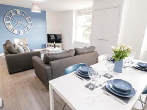 a living room with a table and a clock on the wall at Apartment 6 in Llandudno