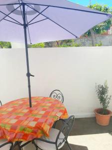 Cataldo Guest House في كابري: طاولة وكراسي مع مظلة على الفناء