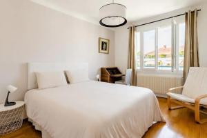 um quarto com uma cama branca, uma cadeira e uma janela em LET'S - 50 m² - T2 Part Dieu / centre - Wifi em Lyon