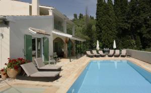 a swimming pool with chairs and a house at Villa Rex - A little piece of heaven! in Nisakion