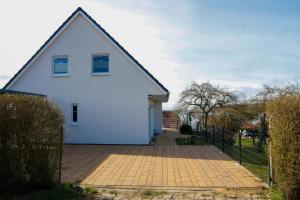 a white house with a fence and a brick driveway at Ferienwohnung am Nordstrand 2 in Alt Schwerin
