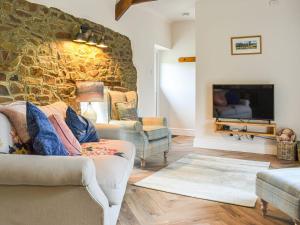 a living room with two couches and a stone wall at Pigaway Cottage in Petrockstow