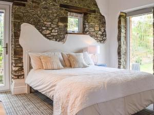 a bedroom with a large bed with a stone wall at Pigaway Cottage in Petrockstow