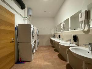 a bathroom with a row of sinks and a refrigerator at Sleep&Go Hostel Ljubljana in Ljubljana