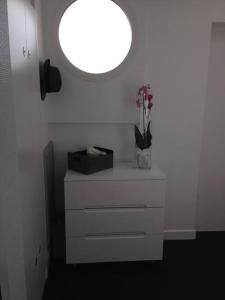 Magnifique Penthouse Pornichet في بورنيشّيه: خزانة بيضاء مع إناء من الزهور عليها