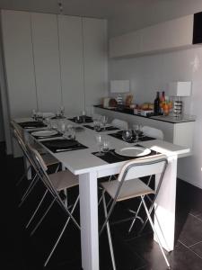 una cocina con una larga mesa blanca con sillas en Magnifique Penthouse Pornichet en Pornichet