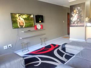 a living room with a couch and a flat screen tv at Goshen Place in Cape Town