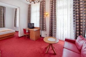 プルハイムにあるHotel Restaurant Mathildenhofのソファ、デスク、テレビが備わる客室です。