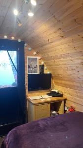 a bedroom with a bed and a desk with a television at Heatherbrae Cosy Wooden Pod in Kyle of Lochalsh