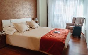 a bedroom with a bed with a chair and a suitcase at A Casa Antiga do Monte Apartamentos Turísticos - Pontecesures in Padrón