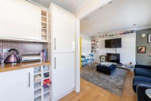 cocina y sala de estar con armarios blancos y sofá azul en Notting Hill Bohemian Apartment, en Londres
