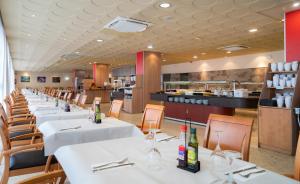 um restaurante com mesas e cadeiras brancas e uma cozinha em Medplaya Hotel Santa Monica em Calella