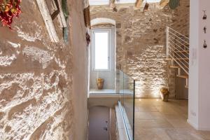 Cette chambre est dotée d'un mur en pierre et d'une fenêtre. dans l'établissement Suite Torre Arcobasso, à Bari