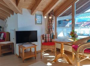 ein Wohnzimmer mit einem TV, einem Tisch und Stühlen in der Unterkunft Falkenhorst in Fischen im Allgäu
