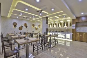 a restaurant with tables and chairs and mirrors on the wall at Rest Inn Dormitory in Vadodara