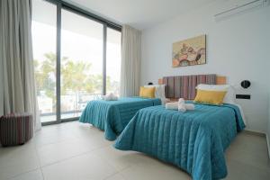 a bedroom with two beds and a large window at Regency Boutique Hotel Holiday Suites in Paphos