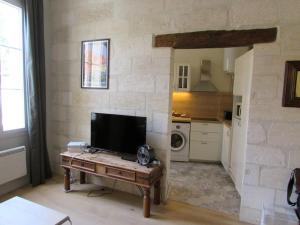 uma sala de estar com uma televisão sobre uma mesa e uma cozinha em Typical 18th century flat, historical center em Avignon