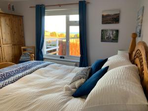 1 dormitorio con 1 cama grande y ventana en Moneydarragh Cottage with uninterrupted mountain and sea views- Hot tub available for hire, en Annalong