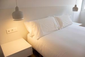 1 dormitorio con cama blanca y mesita de noche en Apartamentos Lucio Rodinso 