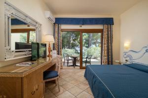 a bedroom with a bed and a desk with a television at Club Esse Palmasera in Cala Gonone