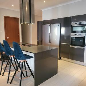 uma cozinha com electrodomésticos de aço inoxidável e bancos de bar azuis em Luxury large 4 bedrooms Beach front house em Sere Kunda