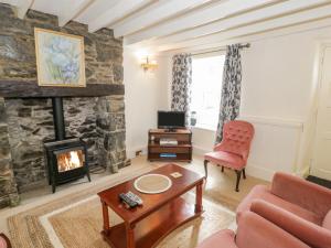 a living room with a fireplace and a red chair at Tudor Cottage in Conwy
