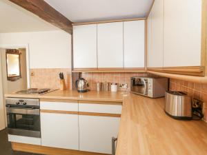 cocina con armarios blancos y suelo de madera en Tudor Cottage, en Conwy
