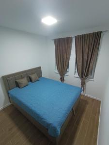 a bedroom with a blue bed and two windows at Leon in Kragujevac