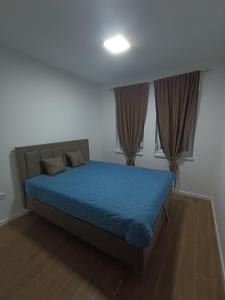a bedroom with a bed with blue sheets and curtains at Leon in Kragujevac