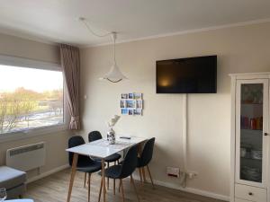 a dining room table with chairs and a tv on the wall at Marina View in Burgtiefe auf Fehmarn 