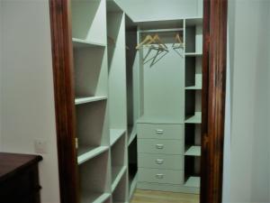 un armario con estanterías y perchas blancas en Casa / Apartamento Azahar, en Ronda