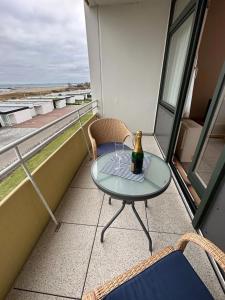 a glass table on a balcony with a bottle of wine at Seepferdchen in Burgtiefe auf Fehmarn  +7 photos