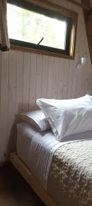 1 cama con almohadas blancas en una habitación con ventana en Molco Alpina, en Molco