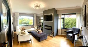 sala de estar con sofá, sillas y TV en Fairways Villa Newcastle, en Newcastle