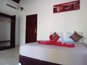 a large white bed with a red blanket on it at Gili Air Santay Bungalows in Gili Air