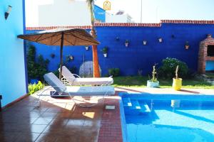 a pool with two lounge chairs and an umbrella at Fancy house in Oualidia