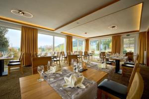 un restaurante con mesas, sillas y ventanas grandes en Nesselwanger Hof, en Nesselwang