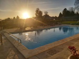 a swimming pool with the sun setting in the background at Solar Quinta de São Carlos in Viseu