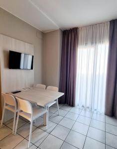 une salle à manger avec une table, des chaises et une télévision dans l'établissement Le Terrazze sul Lago Hotel & Residence, à Padenghe sul Garda