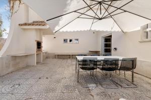 een patio met een tafel en stoelen onder een parasol bij Soltroia Beach Court Villa in Troia