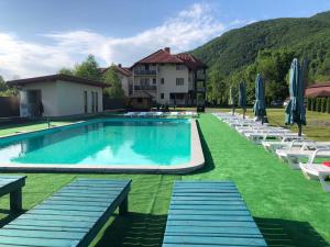a swimming pool with lawn chairs and umbrellas at Приватна садиба Європа in Solochyn