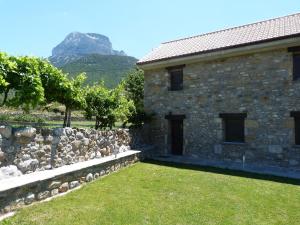 une maison en pierre avec un mur en pierre et une montagne dans l'établissement Puerta de Ordesa Garden, à Laspuña