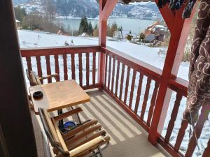 a wooden chair and a table on a balcony with snow at Milijin konak in Zaovine