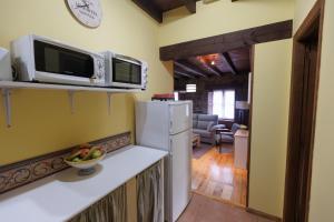 a kitchen with a white refrigerator and a microwave at Hotel Rural El Molino in Soto de Cangas