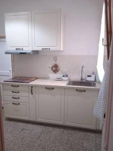 una cocina con armarios blancos y fregadero en Appartamentino in Piazza en Trevignano Romano