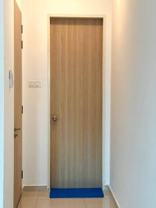 a wooden door with a blue mat in a hallway at KLCC Kampung Baru Cottage - Homestay in Kuala Lumpur