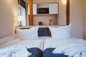 Bett mit weißen Kissen und Waschbecken in einem Zimmer in der Unterkunft Aparthotel Stralsund Studios und Apartments in Stralsund