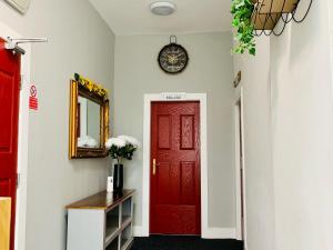 a red door in a hallway with a clock on the wall at Marina Apartments in Bradford